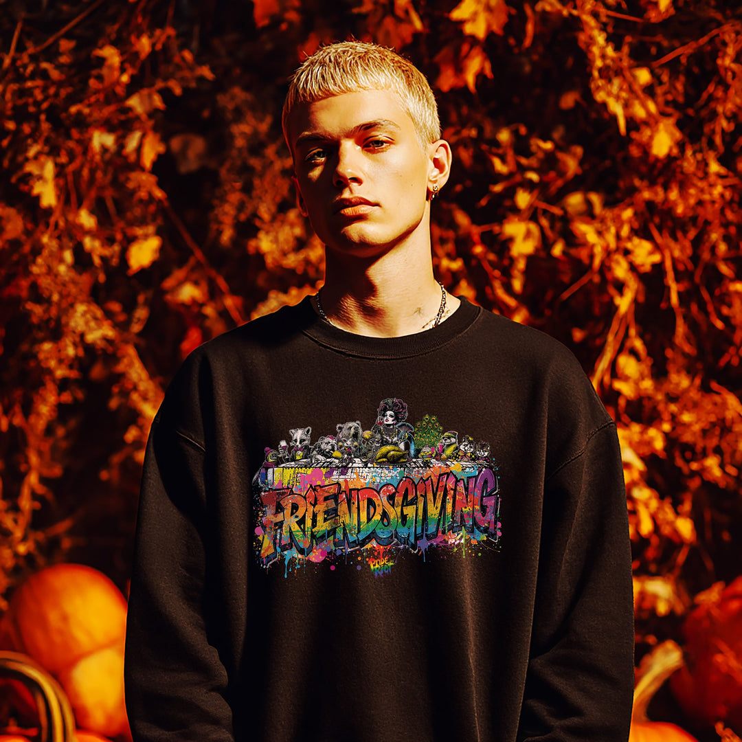 Person wearing a black sweatshirt with 'Friendsgiving' design in front of pumpkins and autumn leaves.