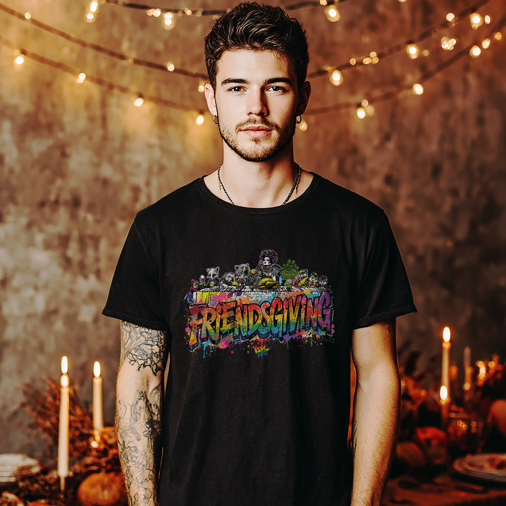 Man wearing a black t-shirt with colorful graphics and text, standing in a warm-lit room with string lights and candles.