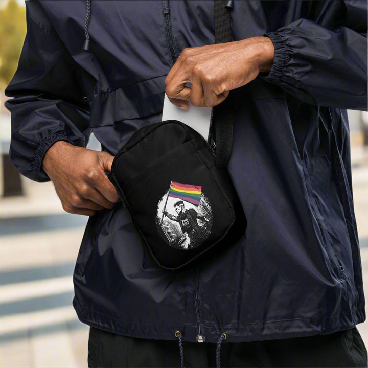 Person wearing a dark jacket holding a black bag with a graphic design.