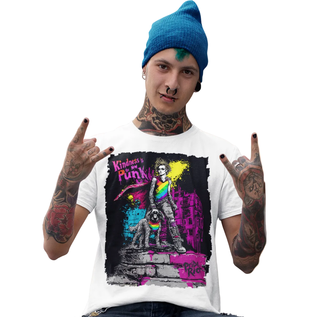 A man wearing a white graphic colorful Pride Riot tee, paired with ripped black jeans and a blue beanie, sitting on a concrete ledge in front of a building.