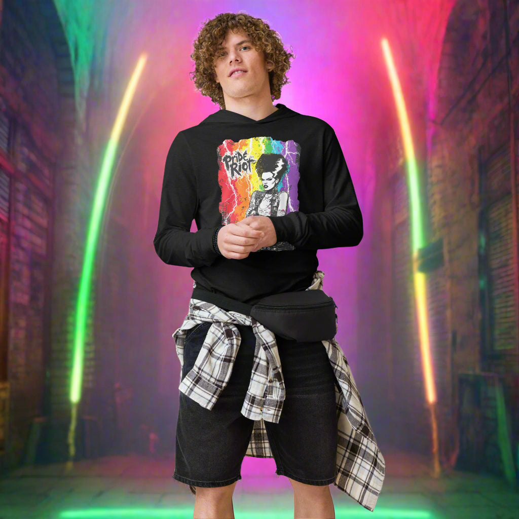 Person wearing a black sweatshirt with colorful graphic design and plaid shirt over black shorts